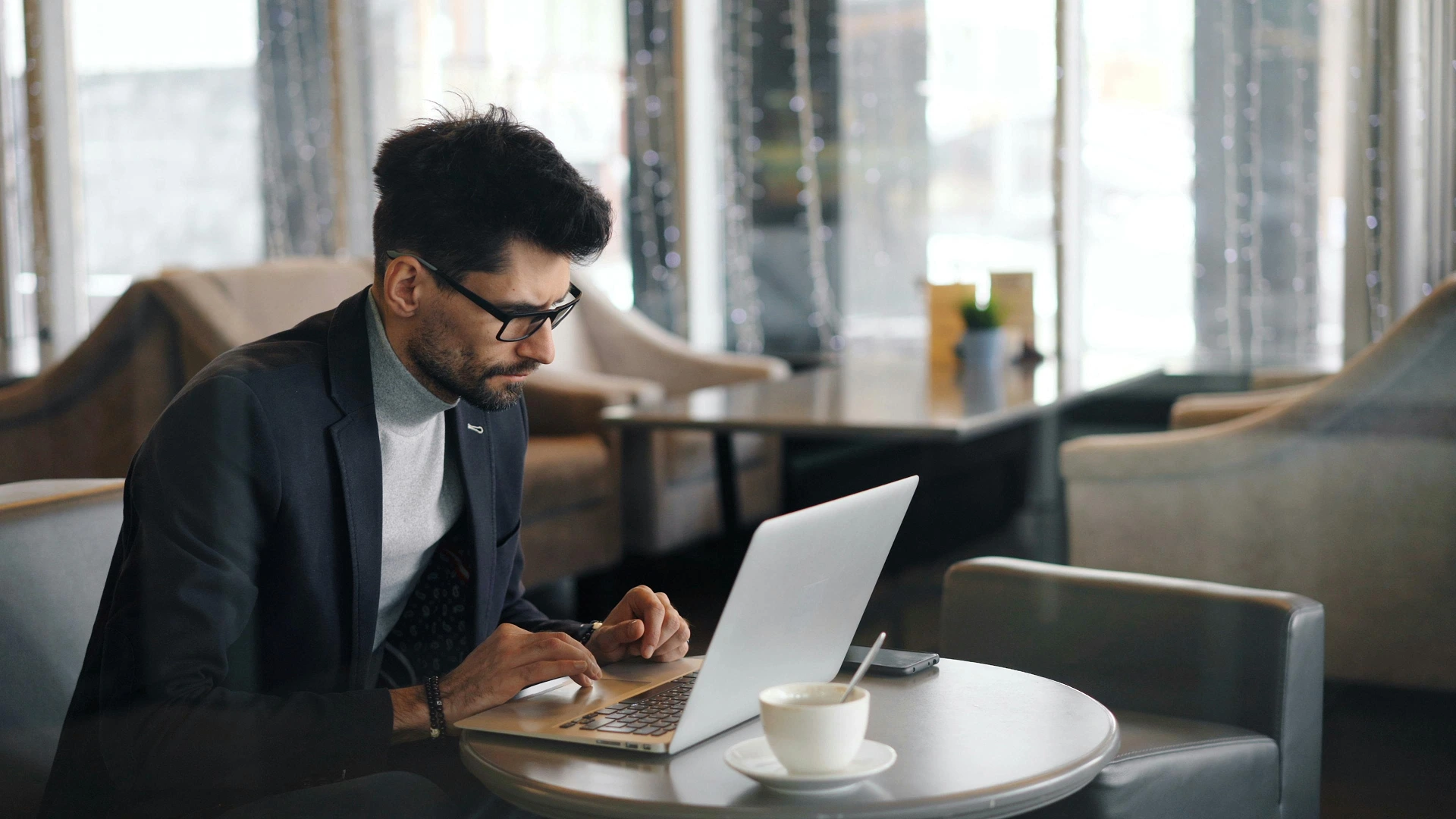 Hombre joven en traje trabajando en su computadora en un entorno corporativo, representando la gestión de microcréditos y estrategias financieras.